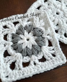 the crochet square is made up of white and gray yarn with a flower in the center