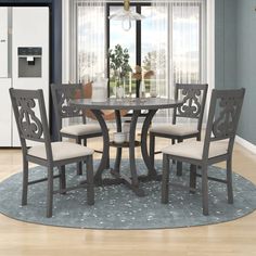 a dining room table with four chairs and a round rug in front of the window