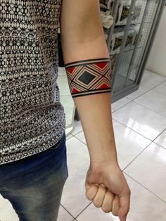 a man with a tattoo on his arm holding the hand of another person's wrist