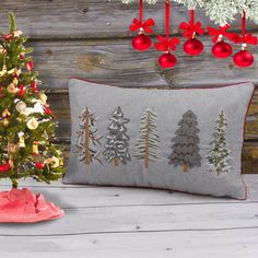 a christmas tree pillow sitting next to a small christmas tree with ornaments on it and a red ornament hanging from the back