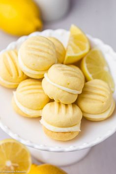 some lemon cookies are on a white plate with lemons in the backgroud