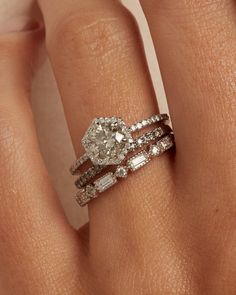 a woman's hand with two wedding rings on her left and an engagement ring on the right