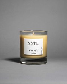 a candle that is sitting on a table next to a gray wall with the words snll written in it