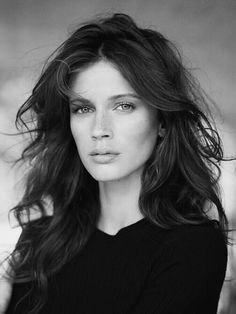 a black and white photo of a woman with long hair, wearing a black top