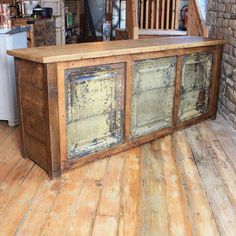 an old wooden counter in the middle of a room with wood floors and brick walls