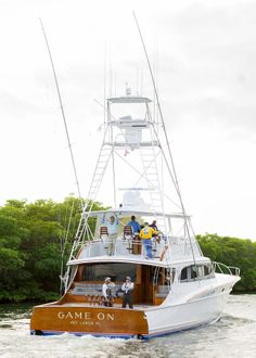 people are standing on the deck of a boat that is in the water near some trees