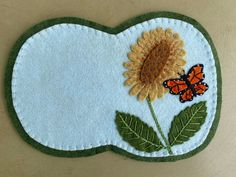 a sunflower and butterfly appliqued on a blue background with green leaves