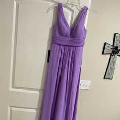 a purple dress hanging up on a wall next to a cross and a white door