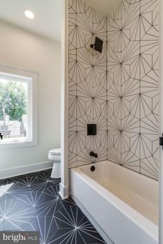 a bathroom with black and white tiles on the floor, walls, and bathtub