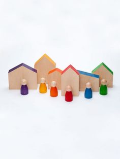 small wooden houses with colored tops on a white surface, set against a row of smaller ones