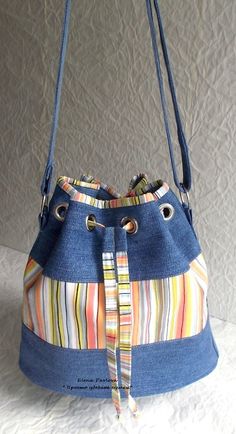 a blue purse with multicolored stripes on the front and side, hanging from a hook