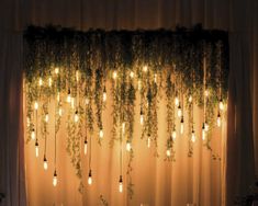 the wedding table is set up with candles and greenery hanging from the ceiling above it