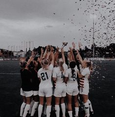 a group of women's soccer players huddle together as confetti flies in the air