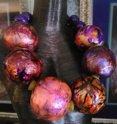 Despite their huge size (3" in front), these beads are light enough to float in water so you needn't have any concerns about neck strain. 32" in length. Each purple, gold, orange, yellow and pink bead is unique yet designed to complement one another. The front beads are spaced with recycled yellow African glass rondelles. Six smaller rich purple beads finish the back. Each bead is finished with a UV protectant to prevent the colors from fading. Closes with a lobster claw clasp. The quintessentia Artistic Beaded Necklace With Large Beads, Unique Faceted Beads For Festival, Unique Large Beads Necklace For Party, Unique Large Glass Beads, Purple Alcohol, Rocker Chic Accessories, Unique Pendant Necklace, Purple Beads, Chest Piece