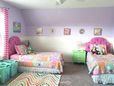 two beds in a room with pink and green decor on the walls, one has a teddy bear sitting on top of it