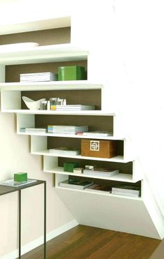 a book shelf sitting on top of a hard wood floor next to a white wall