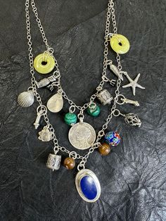 From the private collection of jeweler Keith L Featuring antique Cuban coin and a large lapis stone. Along with other assorted stones and charms Lapis is known as the stone of wisdom, allowing those to wear it to tap into their intuition. This stone invites self expression and creative thinking. Piece #3 Bohemian Medallion Jewelry With Natural Stones, Bohemian Silver Charm Necklace With Gemstone, Silver Bohemian Charm Necklace With Gemstone, Silver Bohemian Charm Necklaces With Gemstones, Bohemian Lapis Lazuli Gemstone Jewelry, Silver Bohemian Lapis Lazuli Necklaces, Bohemian Silver Lapis Lazuli Necklaces, Vintage Lapis Lazuli Round Jewelry, Vintage Lapis Lazuli Jewelry For Gifts