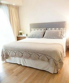 a white bed sitting in a bedroom next to a window with curtains on both sides