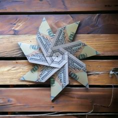 an origami star made out of money sitting on top of a wooden bench