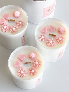 three white containers with pink decorations in them