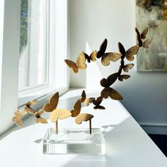 a group of metal butterflies sitting on top of a white table next to a window