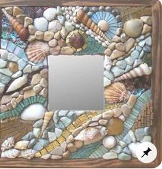 a mirror made out of rocks with shells on the bottom and an image of seashells