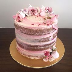 a cake with pink frosting and flowers on a gold plated serving platter