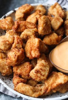 some fried food on a white plate with dipping sauce