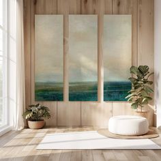 an empty room with three paintings on the wall and a potted plant next to it