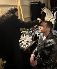 a man getting his hair cut at a barbershop with other people in the background