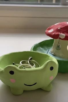 two green dishes with rings in them sitting on a window sill next to a mushroom