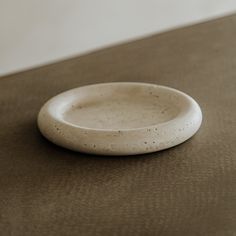 a small white plate sitting on top of a brown tablecloth covered floor next to a wall