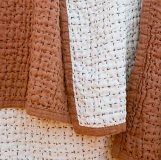 an orange and white blanket with black crosses on it's edges, hanging from a clothes line