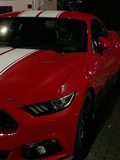 a red and white mustang parked in a garage