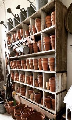 pots and pans are arranged on shelves in a room that is filled with pottery