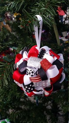 a christmas ornament hanging from a tree decorated with red, white and black ribbon