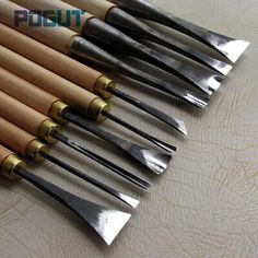 a bunch of knives are lined up on a table top with some gold and silver handles