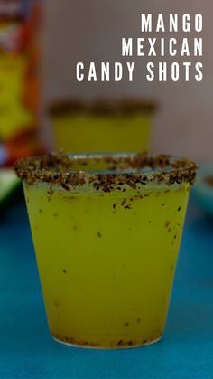 a yellow cup filled with candy shots sitting on top of a blue table next to other food