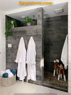 two white towels are hanging on the wall next to a gray tiled shower stall in a bathroom