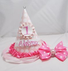 "This adorable party hat will sit upon her head. Birthday wishes are being said. THIS ITEM IS MADE TO ORDER! CONTACT ME BEFORE PURCHASING FOR ESTIMATED COMPLETION DATE. The hat was made out of high quality cardstock and digital patterned paper. The bow topper was made out of grosgrain ribbon and a pink jewel was added to finish it off. The bow is attached to an alligator clip and is removable to wear later. The number 1 was die cut, covered with glitter then attached to a white circle that was e Fun Birthday Party Hat Supplies, Adjustable Mini Hats With Round Crown For Birthdays, Whimsical Adjustable Mini Hats For Birthdays, Adjustable Mini Hats With Round Crown For Birthday, Cute Adjustable Mini Hats For Birthday, Adjustable Round Crown Mini Hats For Birthday, Fun Pink Birthday Costume Hats And Headpieces, Whimsical Adjustable Costume Hats For Birthday, Adjustable Pink Costume Hat For Birthday