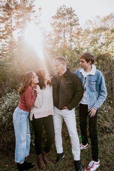 a group of people standing next to each other in front of some trees and bushes