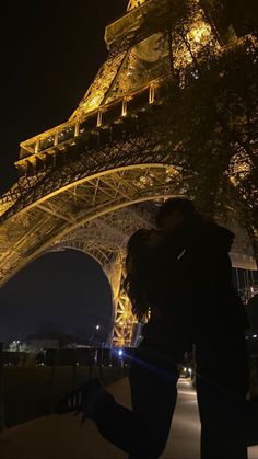 a man and woman kissing in front of the eiffel tower lit up at night