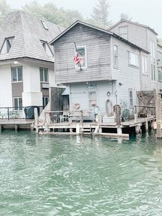 two houses on stilts in the water next to each other with an american flag hanging over them