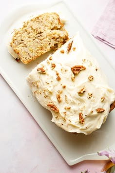 a white plate topped with a piece of cake next to a slice of bread covered in frosting