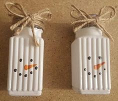 two white salt and pepper shakers decorated like snowmen with carrots on them