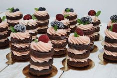 there are many small cakes with frosting and berries on top of each cake,