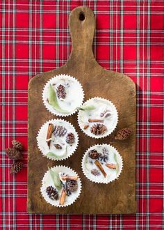 cupcakes with white frosting, cinnamon and pine cones on a wooden cutting board