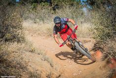 a man riding a bike on top of a dirt trail in the woods and bushes