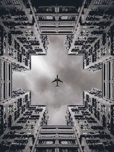 an airplane is flying in the sky between tall buildings