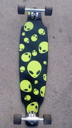 an alien skateboard on the ground with green and black skulls all over it's surface